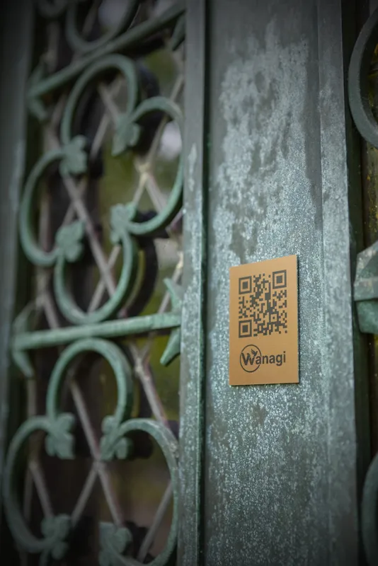 Subtiele bevestiging van de Wanagi QR-code op een decoratief smeedijzeren hekwerk